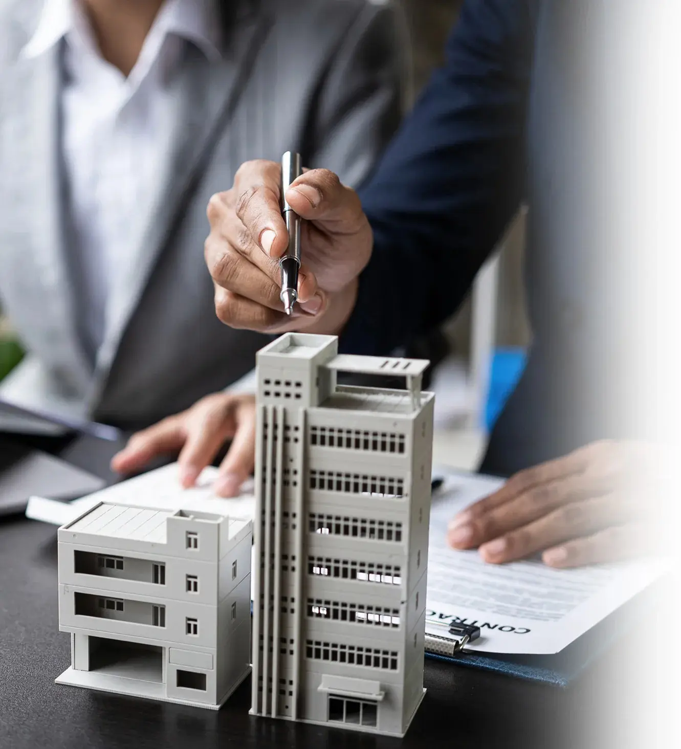 Businesspeople reviewing contract and building models.